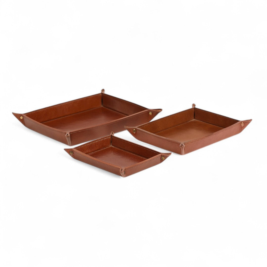 Set of three brown leather trays on a white background