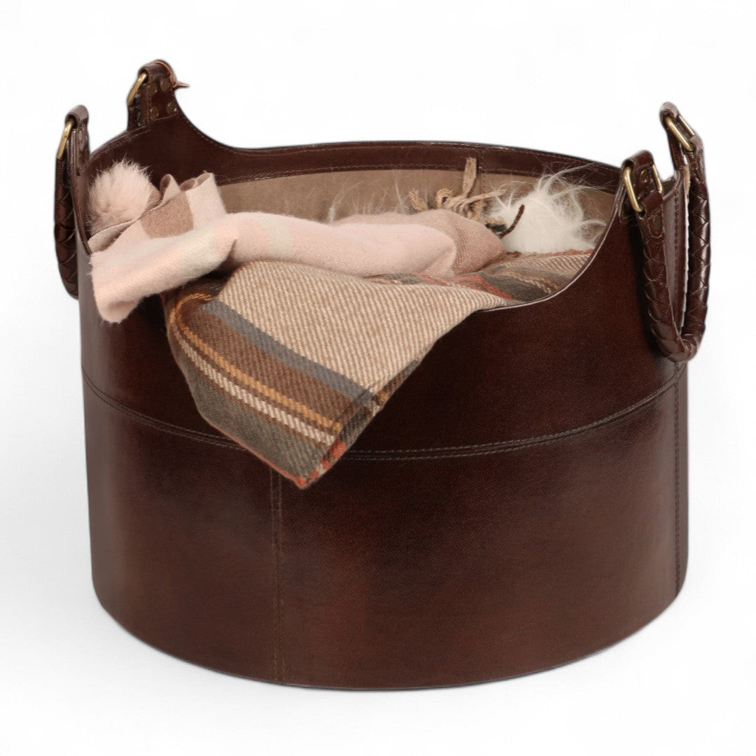 Brown leather pet bed with a blanket and toys on a white background