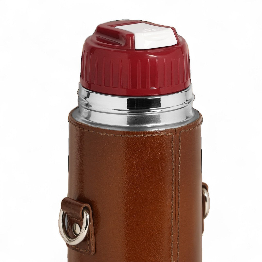 Thermos with brown leather cover and red lid on a white background