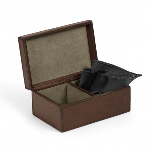 Brown leather jewelry box with a black pocket square inside on a white background