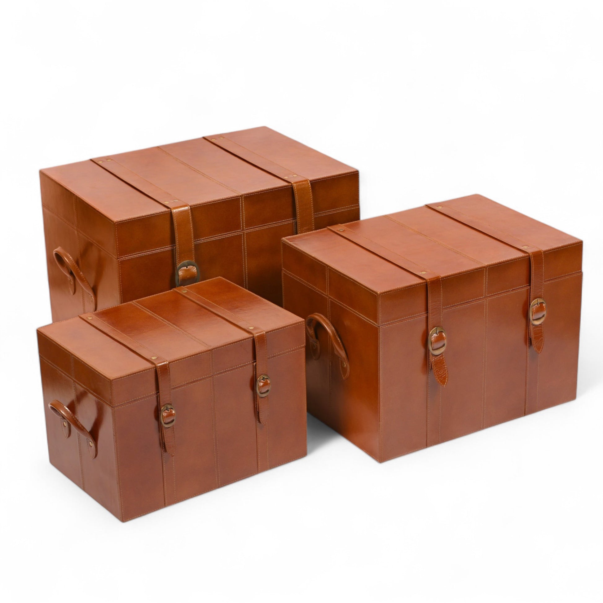 Three brown leather storage trunks of different sizes on a white background