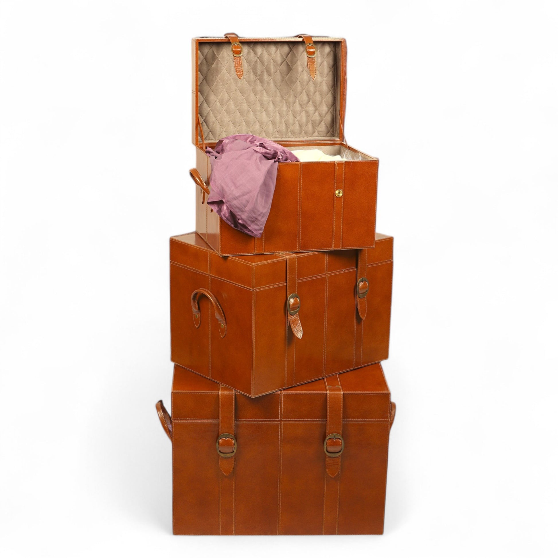 Stack of brown leather storage boxes with a pink garment inside on a white background
